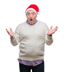 Naklejka premium Handsome senior man wearing christmas hat over isolated background celebrating crazy and amazed for success with arms raised and open eyes screaming excited. Winner concept