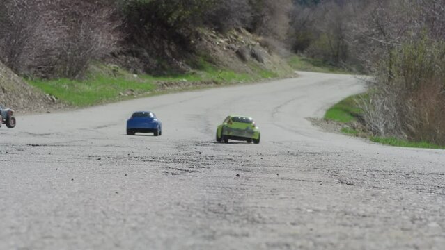 Slow motion of rc cars racing past camera on canyon road