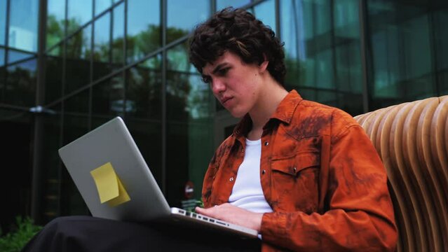 Angry stressed mad business man looking at stuck laptop using pc having problem with computer outdoor, frustrated outraged worker annoyed with online failure, application error or system virus