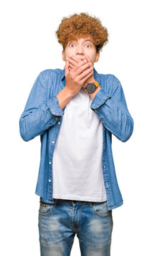 Young handsome man with afro hair wearing denim jacket shocked covering mouth with hands for mistake. Secret concept.