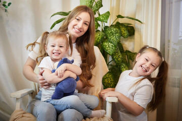 Happy family young mother babysitter relax having fun with cute little children daughters in a living room at home