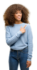 African american woman wearing a sweater cheerful with a smile of face pointing with hand and...