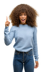 African american woman wearing a sweater pointing finger up with successful idea. Exited and happy. Number one.