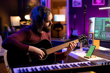 Musician playing acoustic instrument next to greenscreen on smartphone, learning new accords on...