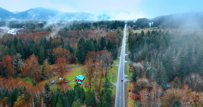 Some cottages nearby the highway in the Mount Rainer national Park, Washington State, the USA. Red car rides by the road in the forest. Top view.