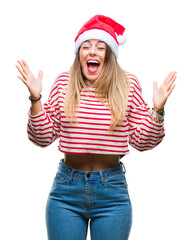 Obraz na płótnie Canvas Young beautiful woman wearing christmas hat over isolated background celebrating mad and crazy for success with arms raised and closed eyes screaming excited. Winner concept