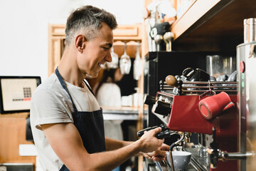 Bartender barista small business owner waiter brewing coffee in coffee machine in the morning...