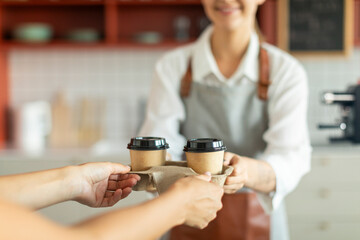 Barista girl giving take away coffee to client at the cafe shop. Takeaway food.