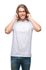Fototapeta premium Young handsome man with long hair wearing glasses over isolated background covering ears with fingers with annoyed expression for the noise of loud music. Deaf concept.