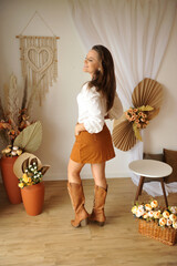 jovem mulher estilo vaqueira com bota cowtry , ambiente interior estilo boho tons marrons