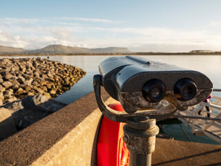 Viewing binoculars with stunning nature ocean and mountain scenery in the background. Cost of Mullaghmore, county Sligo, Ireland. Travel and tourism. Sightseeing Irish fine landscape.