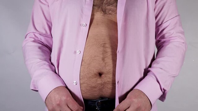 A man trying to fasten a pink shirt but he is too over weight to fasten it, and need to go on a diet, dieting loosing weight concept
