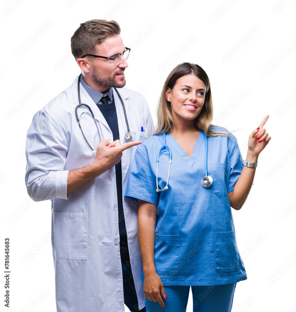 Canvas Prints Young couple of doctor and surgeon over isolated background with a big smile on face, pointing with hand and finger to the side looking at the camera.