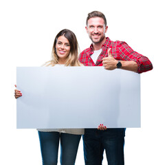 Young couple together holding blank banner over isolated background happy with big smile doing ok...