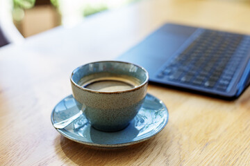 Workspace. Ceramic Coffee Cup on Wooden Table with Laptop