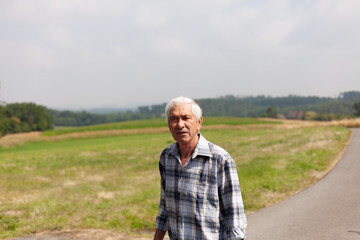 Peaceful and contemplative nature of an elderly man taking a leisurely walk along a rural road, embracing the beauty and simplicity of countryside living