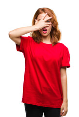 Young beautiful woman over isolated background peeking in shock covering face and eyes with hand, looking through fingers with embarrassed expression.