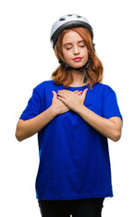Young beautiful woman wearing cyclist helmet over isolated background smiling with hands on chest with closed eyes and grateful gesture on face. Health concept.