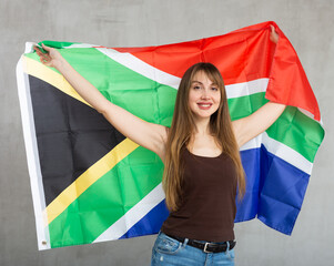Young pretty woman posing cheerfully with flag of south african republic