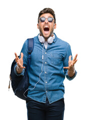 Young handsome tourist man wearing headphones and backpack over isolated background crazy and mad...