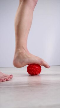 Close-up of a woman's foot on a massage ball with spikes. Vertical video. 