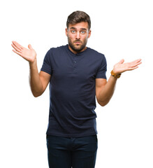 Young handsome man over isolated background clueless and confused expression with arms and hands...