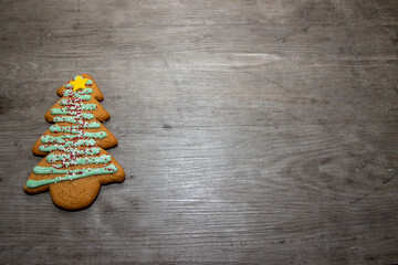 A delicious Christmas tree ginger bread with green icing, sprinkles and a yellow star on a wooden...