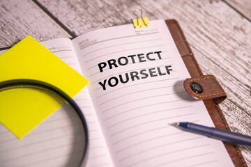 PROTECT YOURSELF text written on yellow paper with notebook - Powered by Adobe