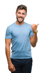 Young handsome man over isolated background smiling with happy face looking and pointing to the side with thumb up.