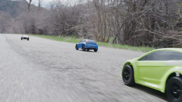 Steady cam past colorful rc cars on road in slow motion