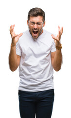 Naklejka premium Young handsome man wearing glasses over isolated background celebrating mad and crazy for success with arms raised and closed eyes screaming excited. Winner concept