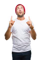 Young handsome man over isolated background amazed and surprised looking up and pointing with fingers and raised arms.