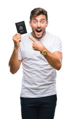 Young handsome man holding passport of united states over isolated background very happy pointing...