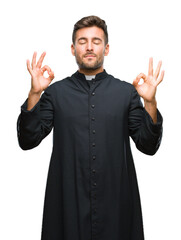 Young catholic christian priest man over isolated background relax and smiling with eyes closed doing meditation gesture with fingers. Yoga concept.