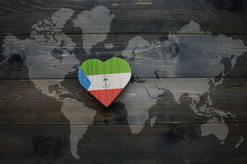 wooden heart with national flag of equatorial guinea near world map on the wooden background.