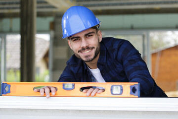 happy builder checking level of wood at construction site