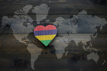wooden heart with national flag of mauritius near world map on the wooden background.