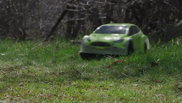 Small green RC car driving out of forest - low, slow motion shot
