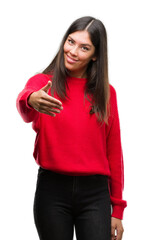 Young beautiful hispanic wearing red sweater smiling friendly offering handshake as greeting and welcoming. Successful business.