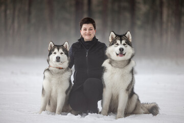 Happy Young Girl and Two Malamute Dogs in Snowy Hazy Mist Foggy Backgroud