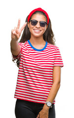 Obraz na płótnie Canvas Young beautiful arab woman wearing sunglasses over isolated background smiling with happy face winking at the camera doing victory sign. Number two.