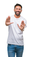 Naklejka premium Adult hispanic man over isolated background afraid and terrified with fear expression stop gesture with hands, shouting in shock. Panic concept.