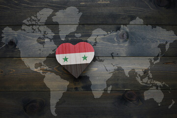 wooden heart with national flag of syria near world map on the wooden background.