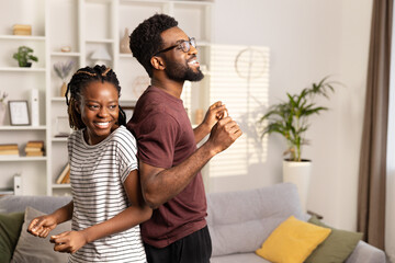 Joyful Young Couple Sharing a Dance in Their Cozy Living Room, Radiating Positive Energy and Togetherness in a Casual Setting.