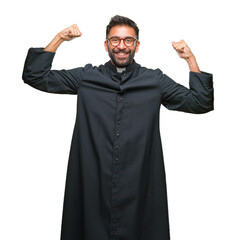 Adult hispanic catholic priest man over isolated background showing arms muscles smiling proud. Fitness concept.