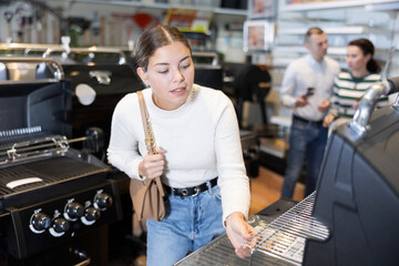 Young woman shopping at garden supermarket - choosing a new grill for frying meat