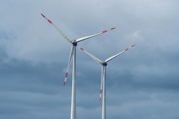 Two wind turbines against the cloudy sky