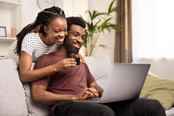 Happy African American Couple Shopping Online Together At Home On Laptop. Love, Technology, and...