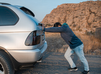 the man was pushing the broken down car on the road. stock photo