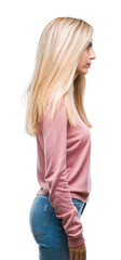 Young beautiful blonde woman wearing pink winter sweater over isolated background looking to side, relax profile pose with natural face with confident smile.